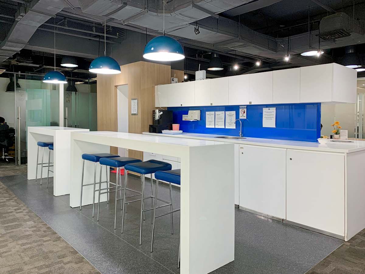 Modern coworking space with sleek high tables, vibrant blue accents, and ample lighting.