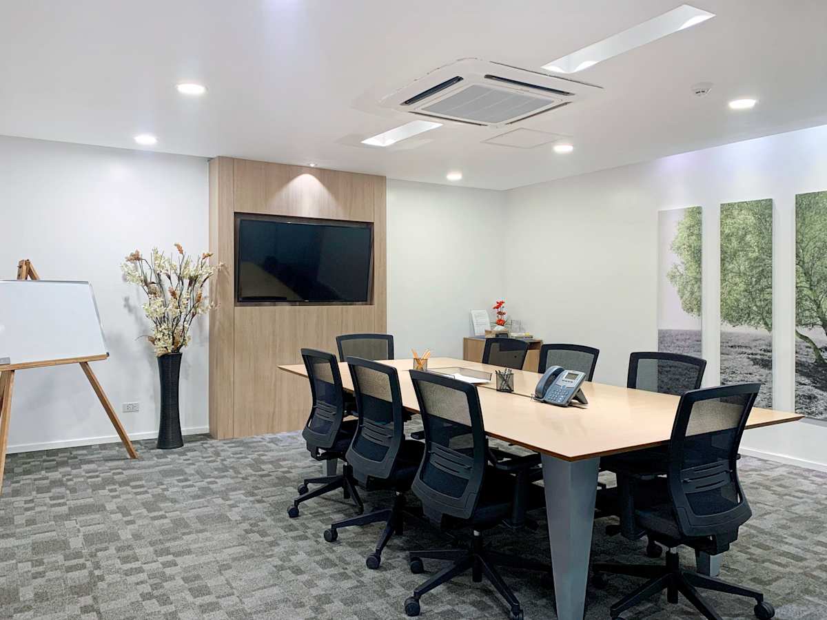 Modern meeting room with ample seating, sleek conference table, and AV setup. Bright and inviting.
