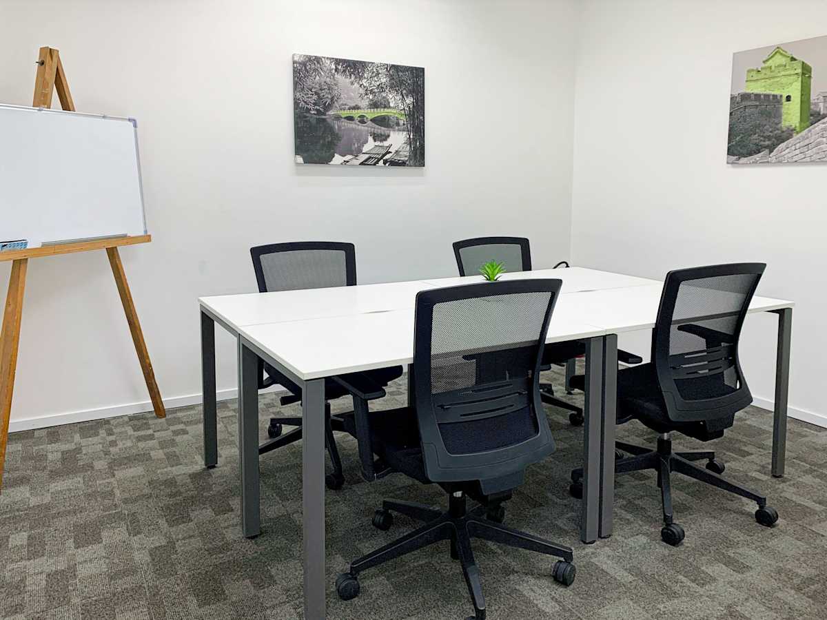 Modern office with a collaborative table, ergonomic chairs, and a presentation easel.