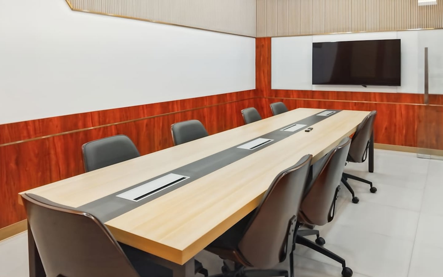 Modern conference room with sleek table, ergonomic chairs, and wall-mounted TV for presentations.