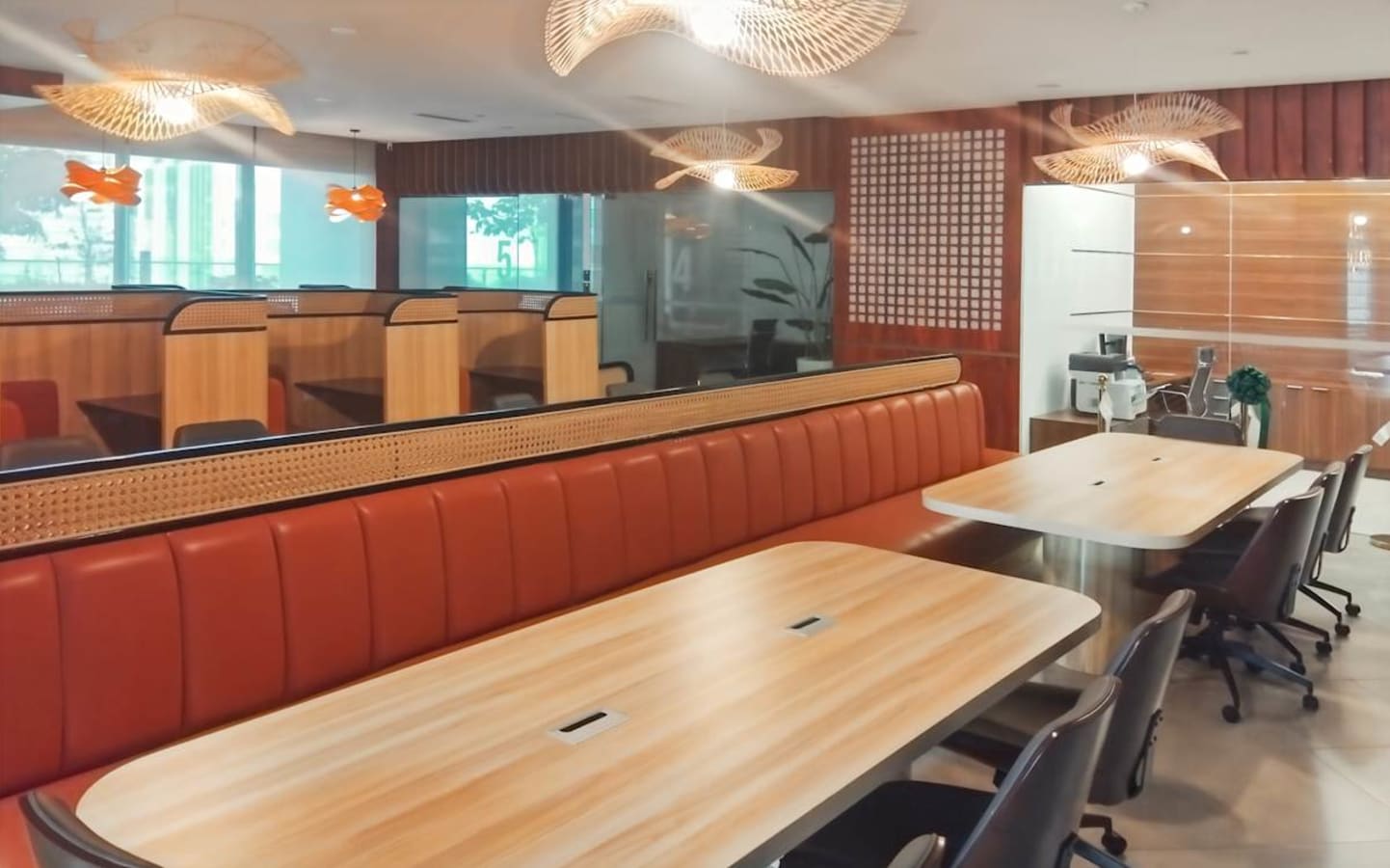 Modern coworking area with sleek booths, shared tables, and stylish pendant lighting.