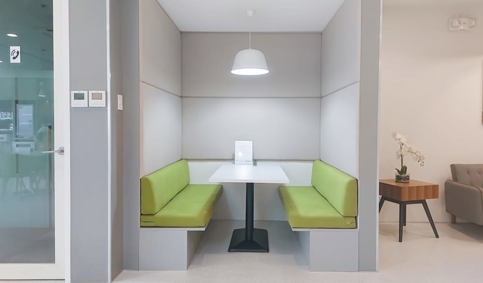 Modern booth with soft green seating, perfect for meetings or focused work. Bright, inviting ambiance.