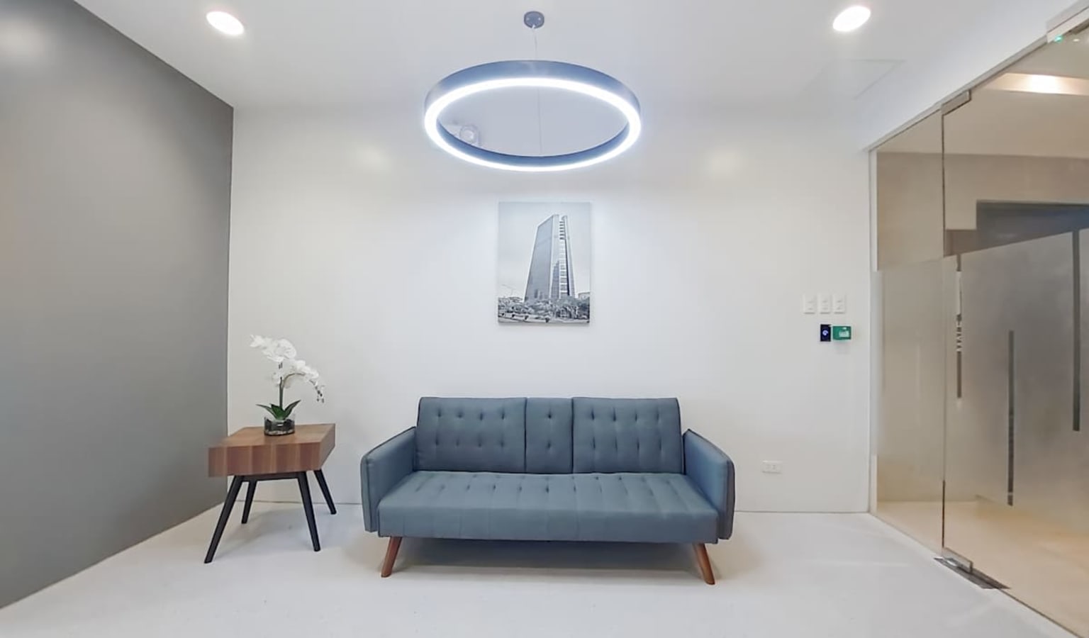 Modern office lobby with sleek sofa, stylish lighting, and minimal decor. Ideal for welcoming clients.