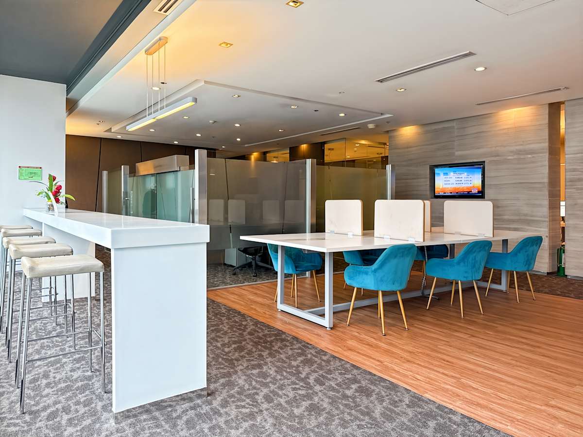 Modern coworking area with plush seating, high stools, and private workspaces. Cozy and stylish.