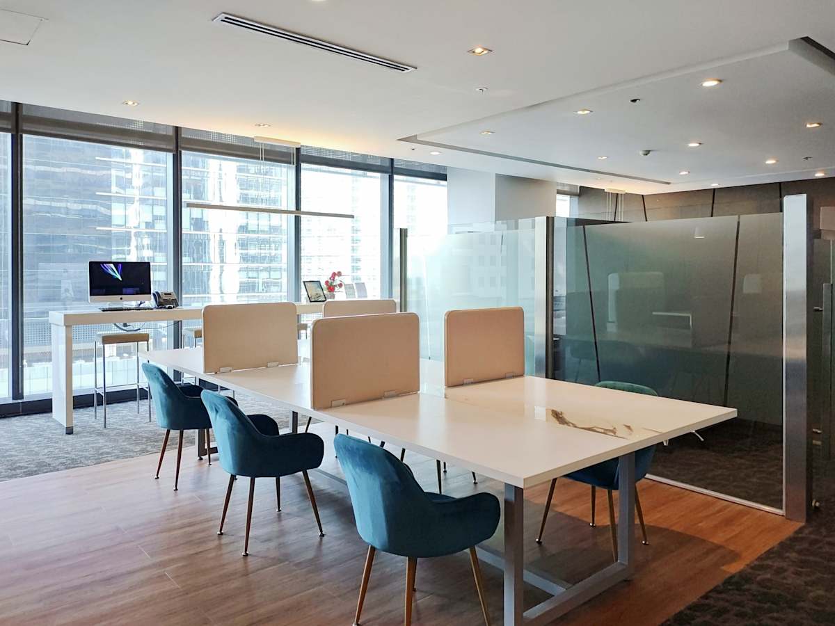 Modern coworking space with sleek desks, blue chairs, and ample natural light. Ideal for collaboration.