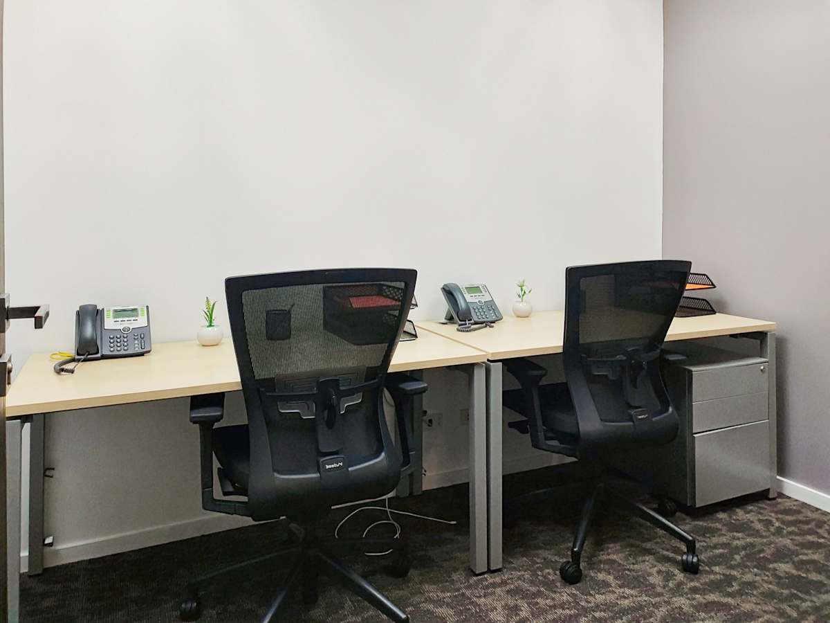 Modern workspace with ergonomic chairs, dual desks, and organized essentials for productivity.