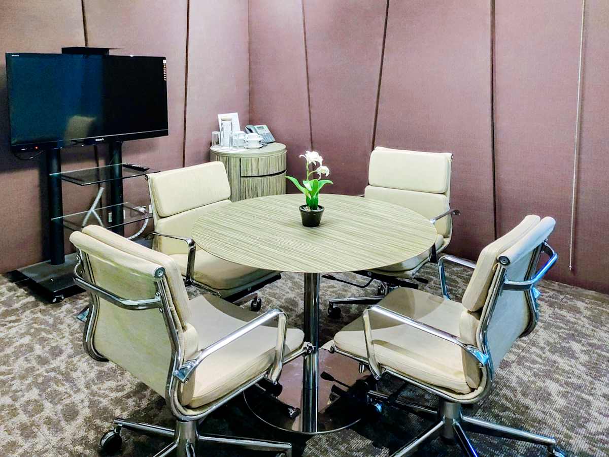 Modern meeting room with sleek chairs, round table, and a large screen for presentations.