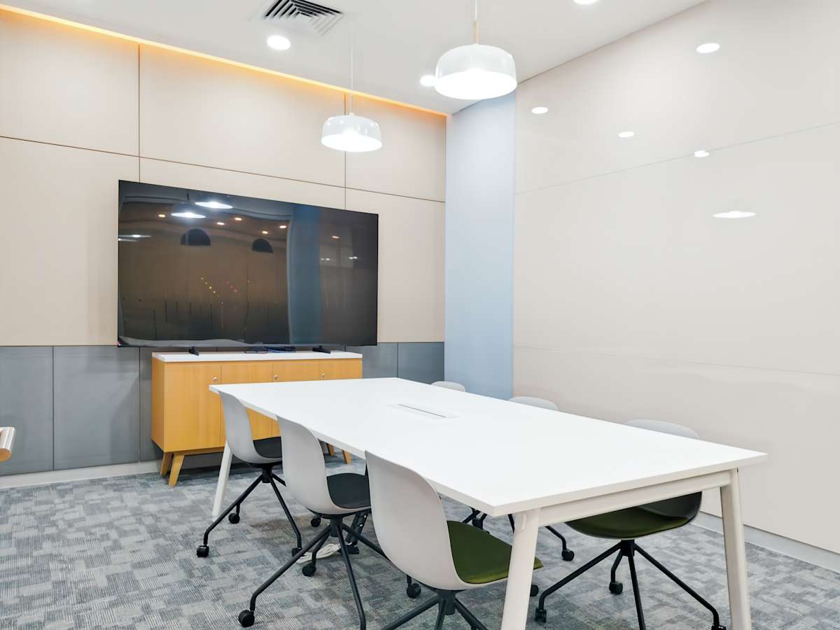 Modern meeting room with sleek table, ergonomic chairs, and large screen for presentations.