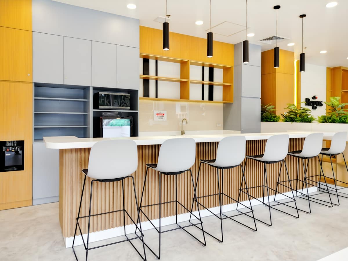 Modern coworking kitchen area with sleek bar seating and stylish lighting. Perfect for casual meetings.