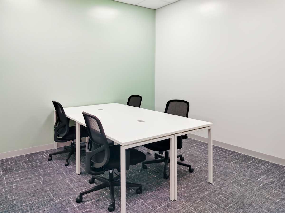 Modern office space with a minimalist design, featuring a sleek table and ergonomic chairs.