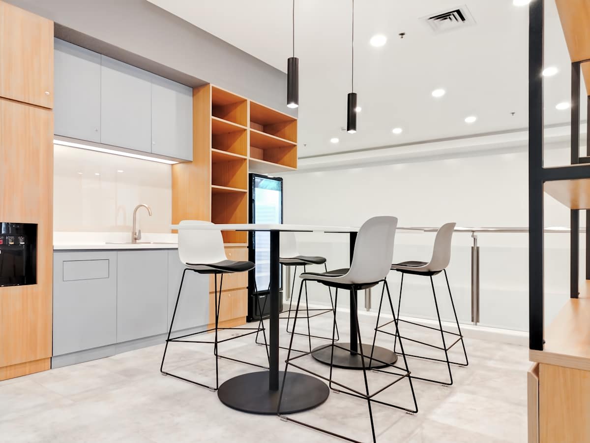 Modern coworking space with sleek kitchen, high-top tables, and ample natural light.