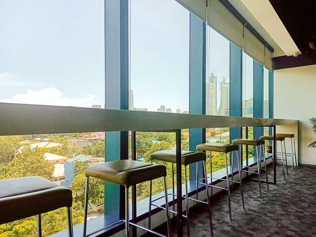 Bright coworking area with panoramic city views and sleek high-top seating.