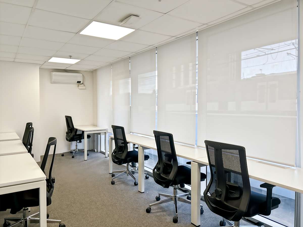 Modern coworking space with ergonomic chairs, ample natural light, and a minimalist design.
