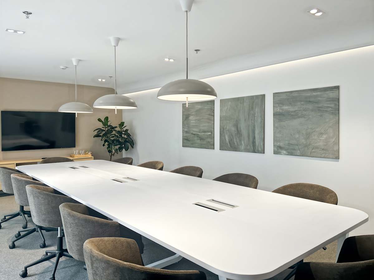 Sleek conference room with modern lighting, plush seating, and a large screen, perfect for meetings.