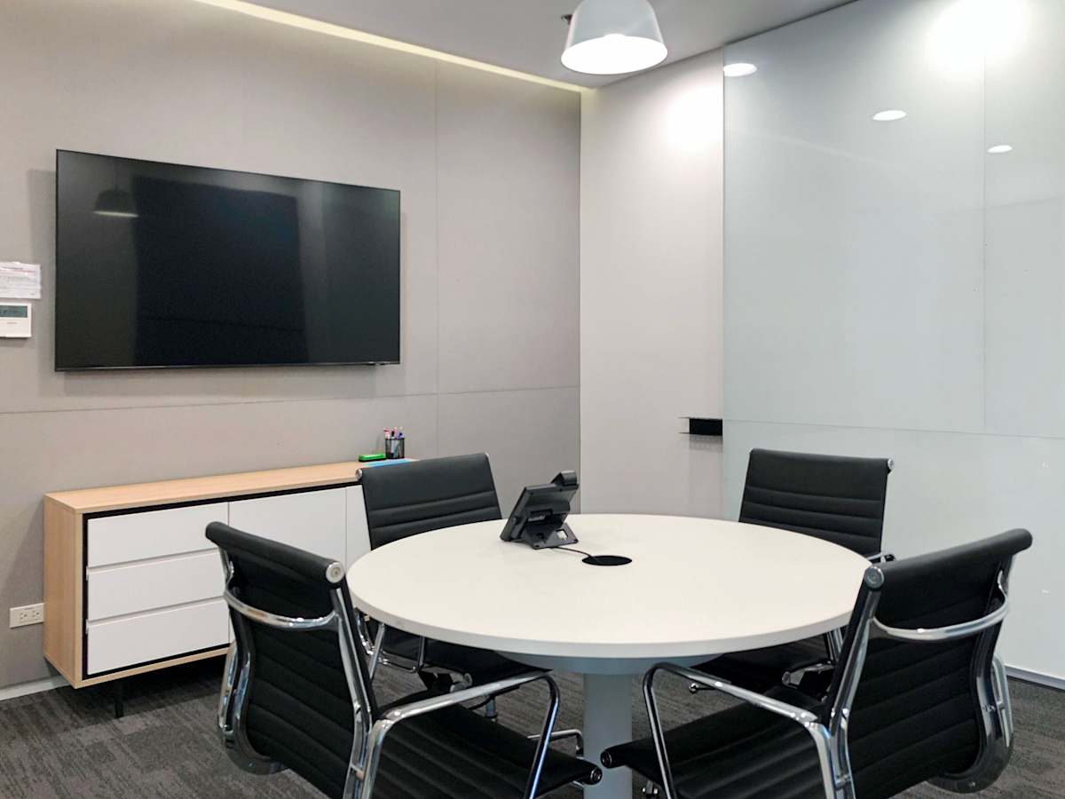 Sleek meeting room with modern amenities, featuring a round table, leather chairs, and a flat screen.