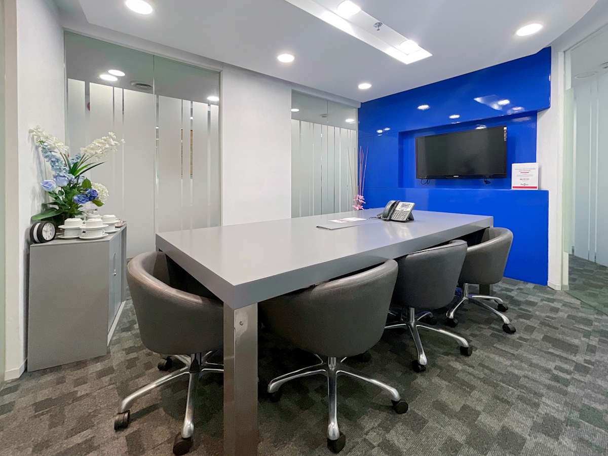 Modern meeting room with sleek table, blue accent wall, smart TV, and ample seating in Metro Manila.