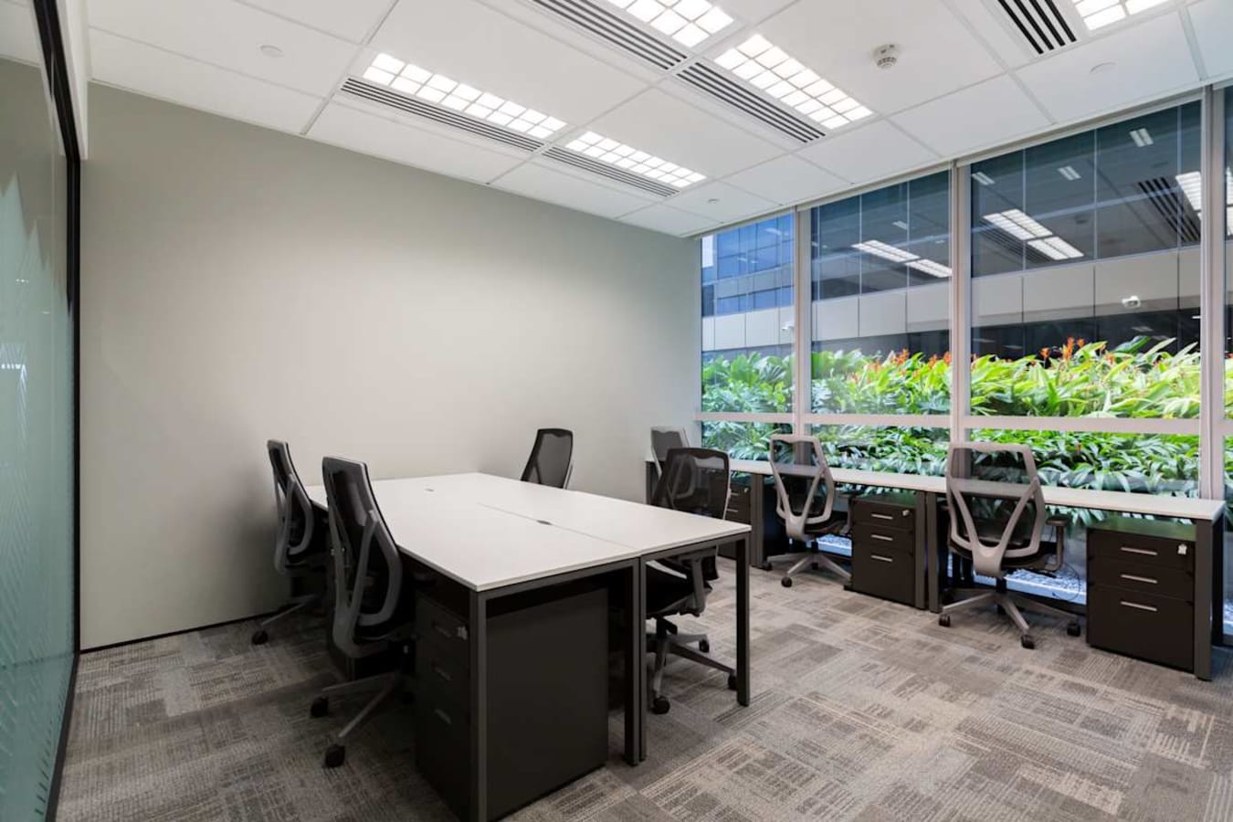 Bright coworking space with modern chairs, large windows, and greenery views in Paya Lebar.