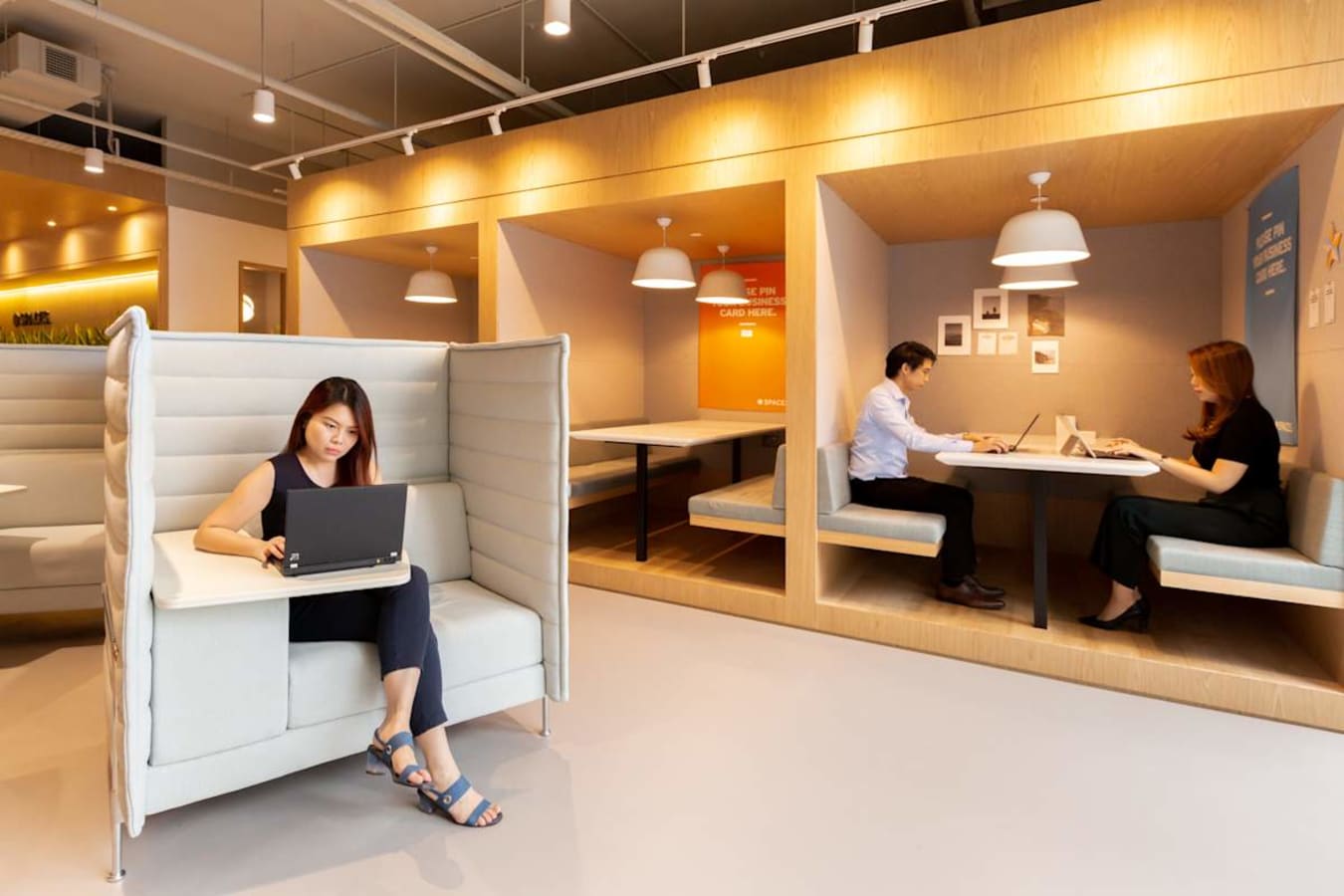 Flexible coworking space with modern booths, ample lighting, and a collaborative atmosphere.