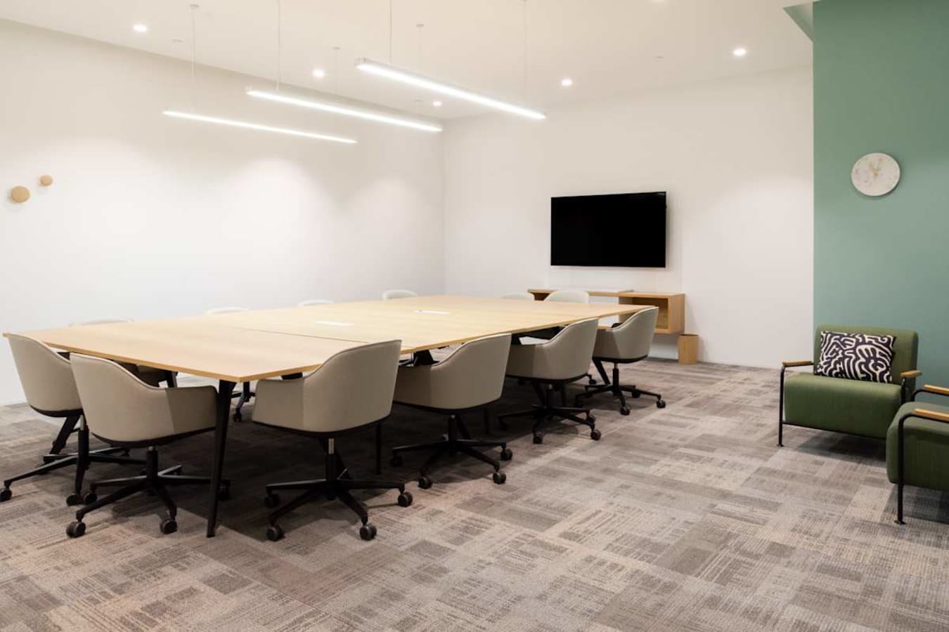 Modern coworking space with ample seating, sleek lighting, and a conference-ready setup.