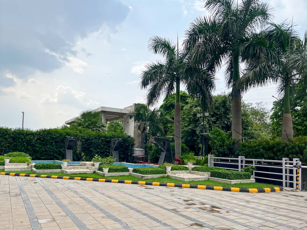 Serene outdoor area at a Noida-Greater Noida coworking space, featuring lush greenery and palm trees.