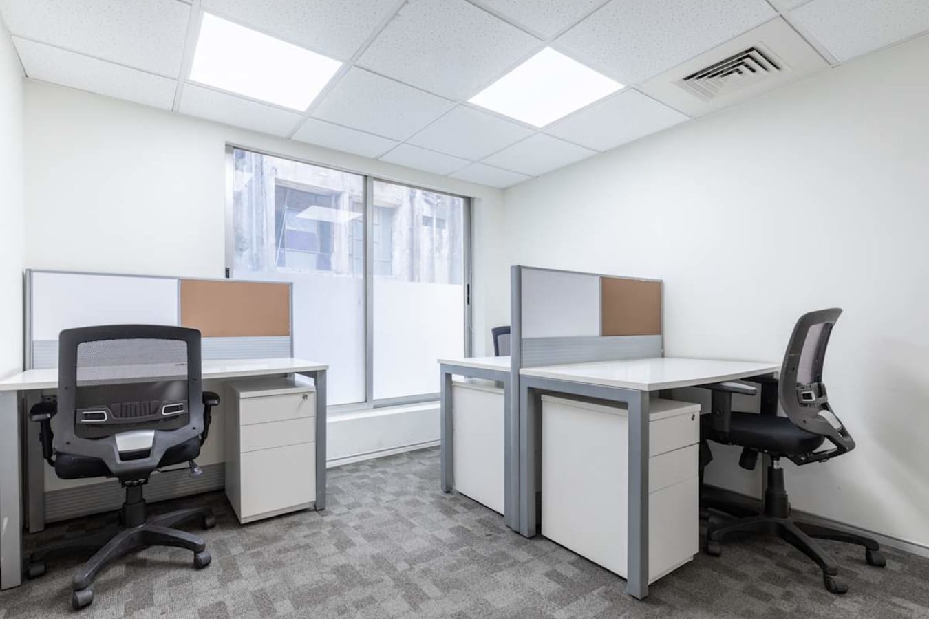 Bright coworking area with modern desks, ergonomic chairs, and ample natural light.