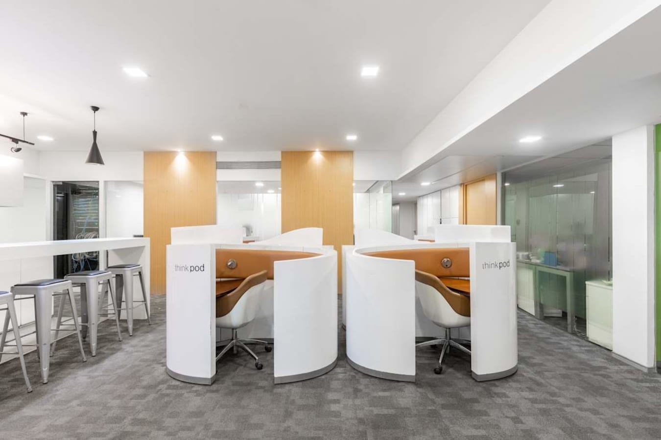Modern coworking area with private pods, ample lighting, and sleek high-top seating. Ideal for focused work.
