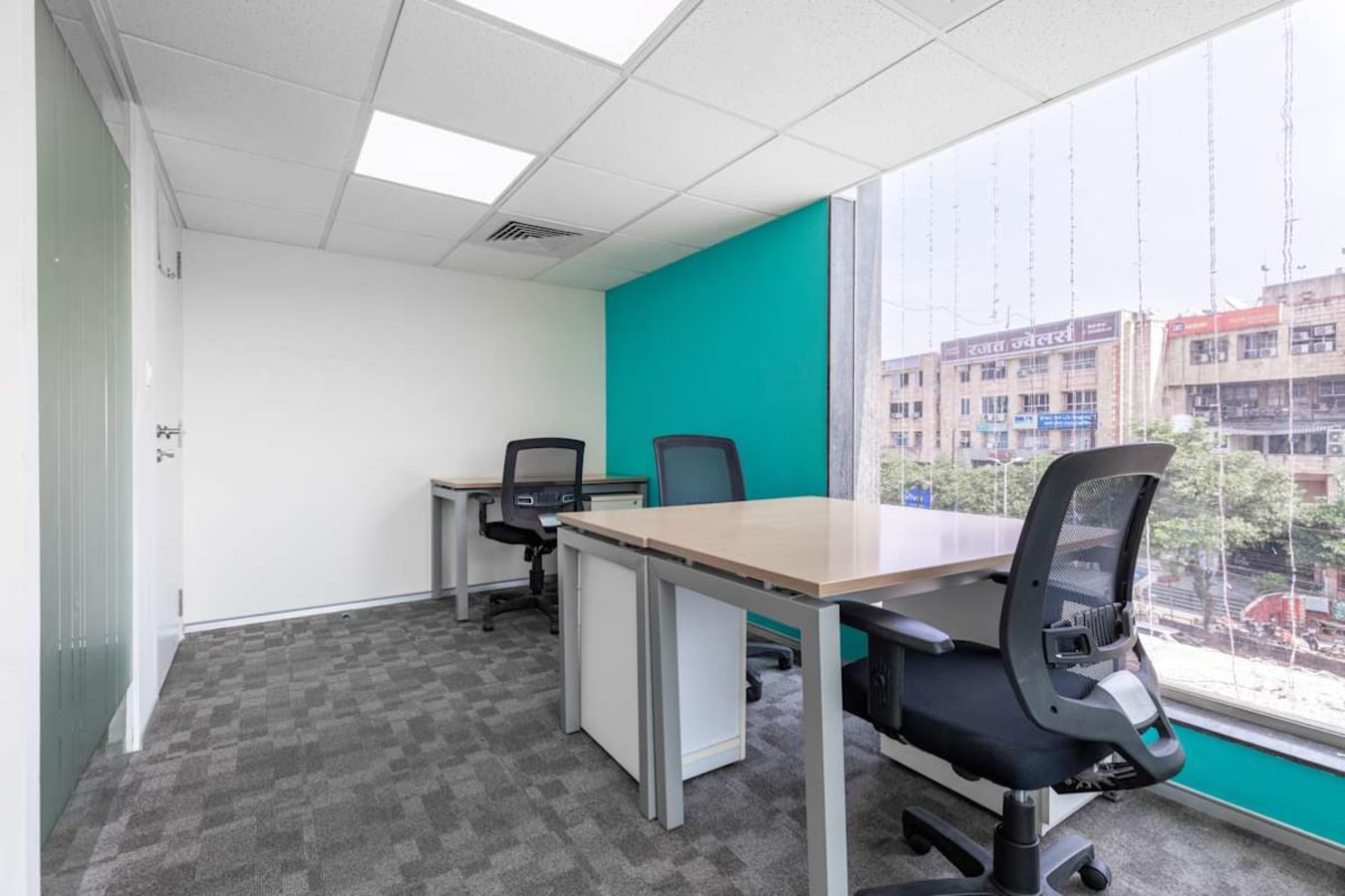 Bright, modern coworking space with large windows, ergonomic chairs, and a vibrant accent wall.