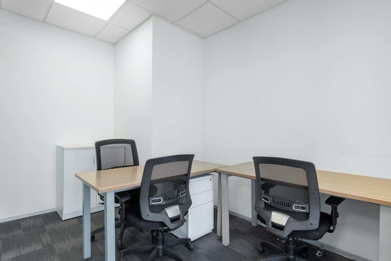 Modern, minimalist workspace with ergonomic chairs and ample lighting, perfect for focused work.
