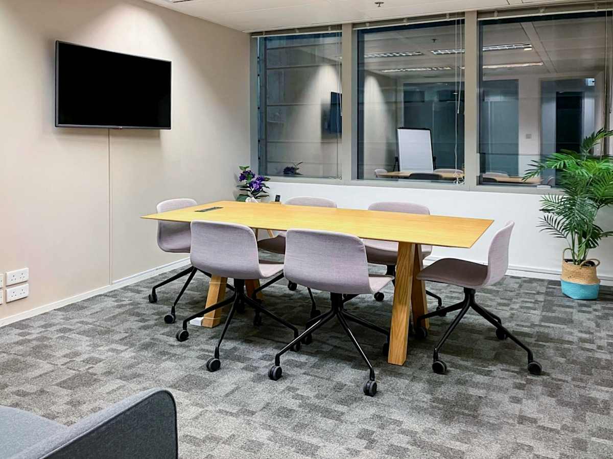 Meeting room with modern furnishings, natural light, and equipped with a wall-mounted screen. Perfect for collaboration.