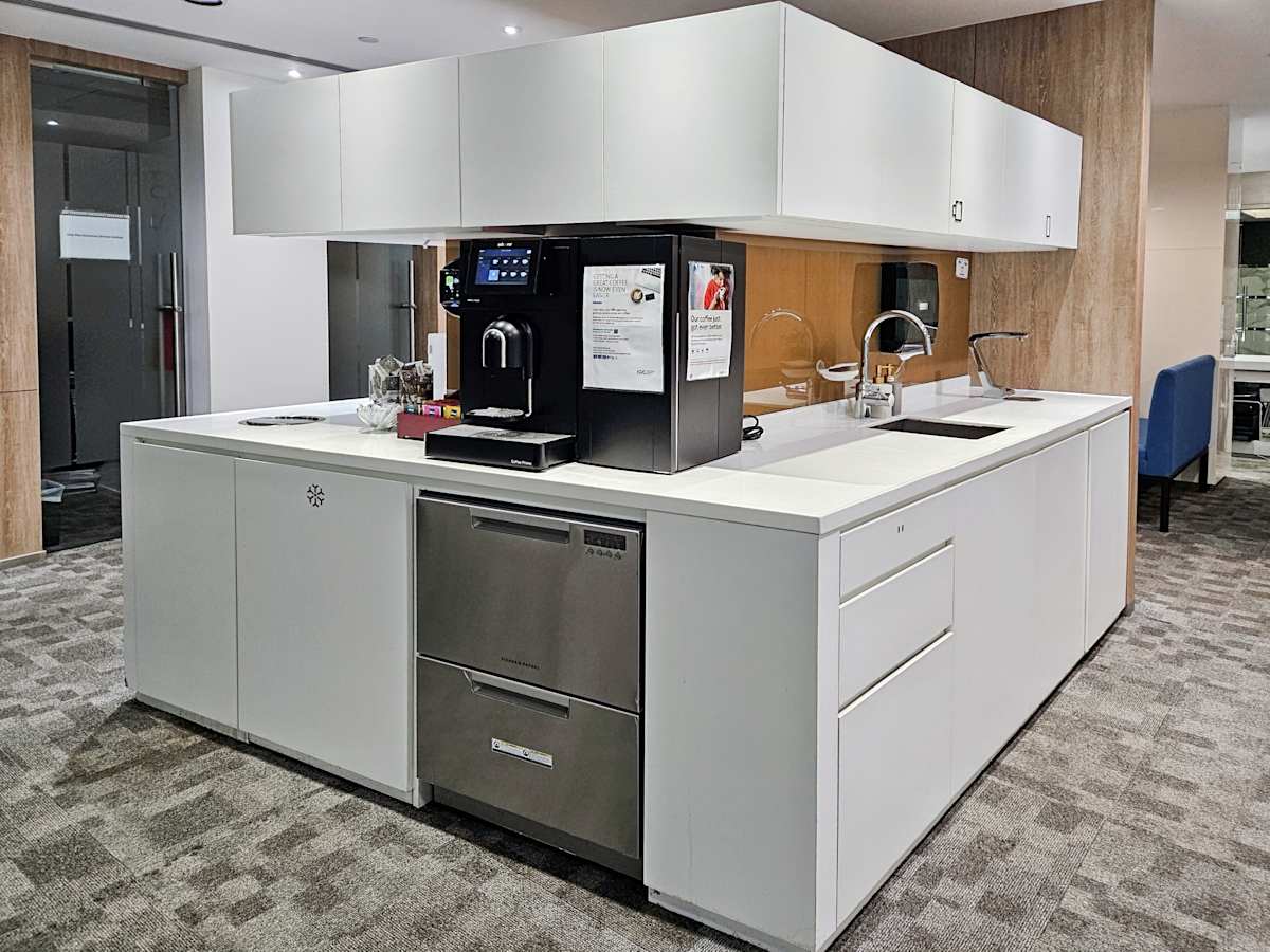 Modern coworking kitchen with sleek cabinetry, high-end coffee machine, and ample counter space.
