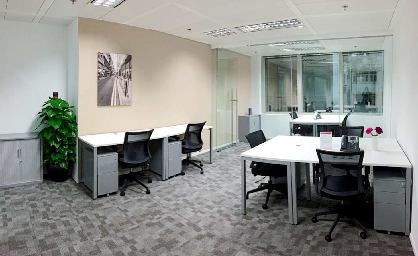 Modern coworking space with sleek desks, ergonomic chairs, and natural light on Queen's Road Central.