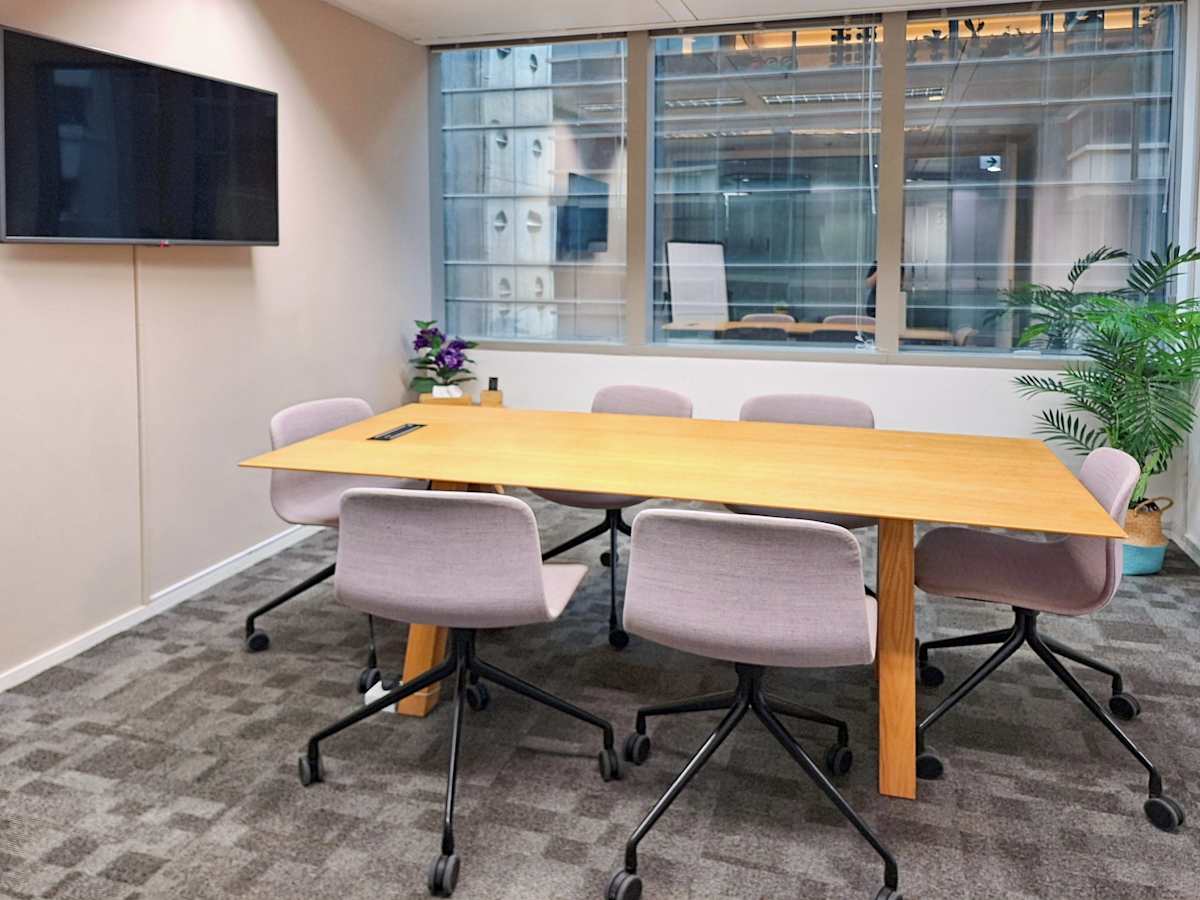 Modern meeting room with natural light, sleek wooden table, and comfortable seating in Queen's Road Central.