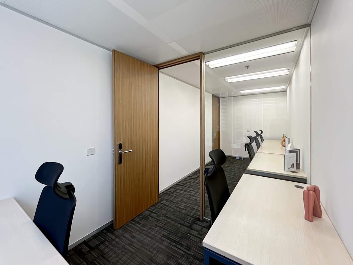 Modern coworking space with sleek desks, ergonomic chairs, and private meeting room.
