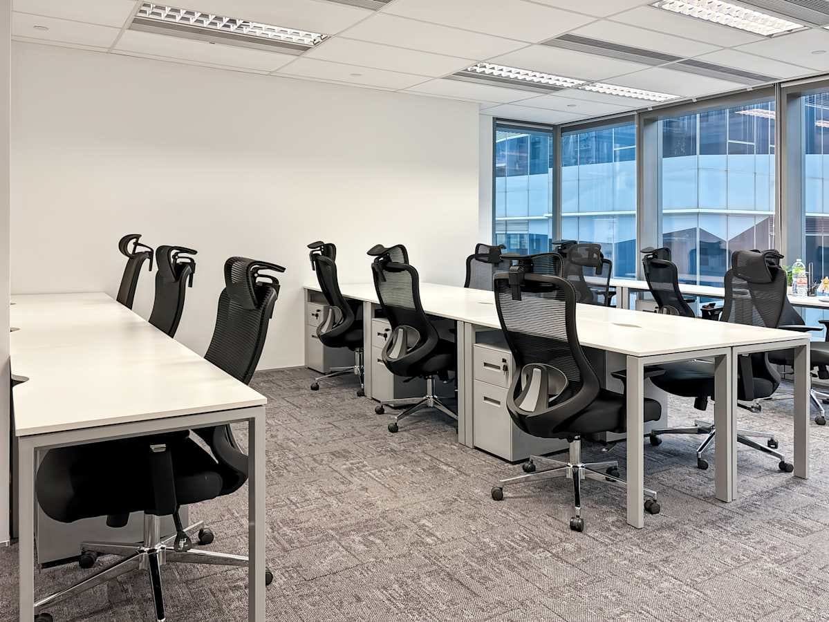 Bright coworking area with ergonomic chairs, spacious desks, and abundant natural light.