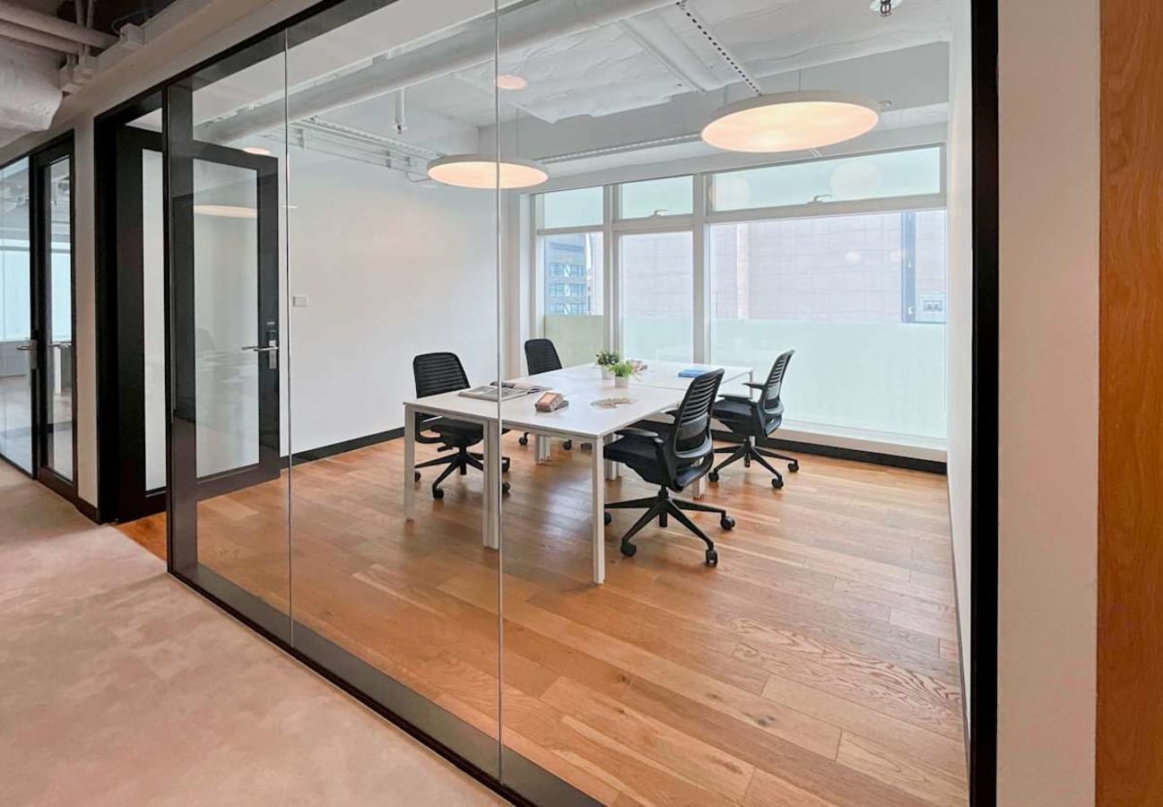 Modern meeting room with glass walls, ample natural light, and sleek furnishings. Ideal for collaboration.
