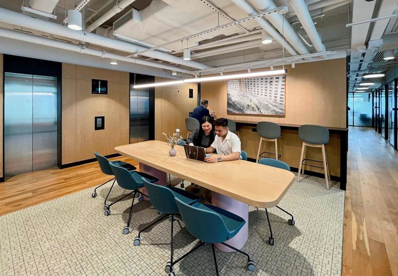 Modern coworking space with open seating, warm lighting, and collaborative work areas.