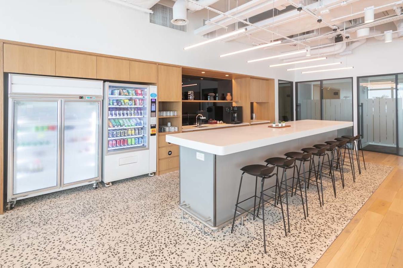 Modern coworking space with sleek kitchen, ample seating, and vibrant vending amenities.