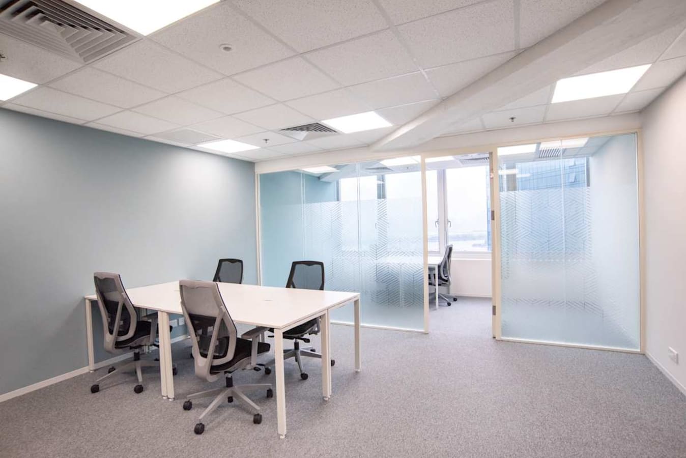 Modern coworking space with stylish chairs, modular tables, and a private meeting room on Wai Yip Street.