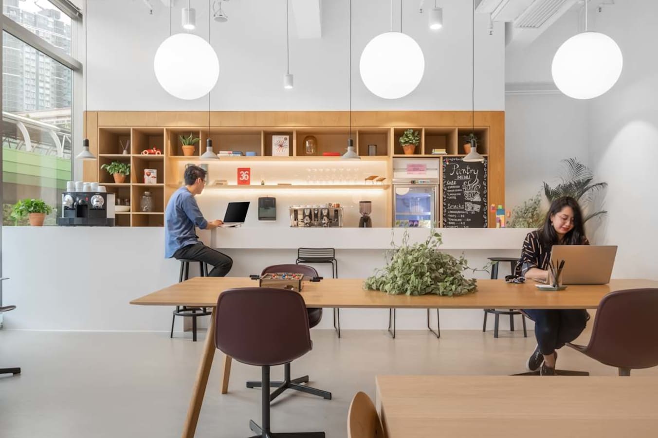 Modern coworking space with open seating, communal tables, and a welcoming pantry area.