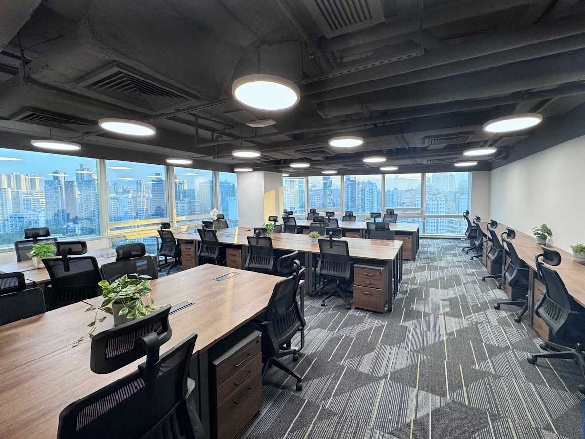 Modern coworking space with city views, ergonomic chairs, and abundant natural light.
