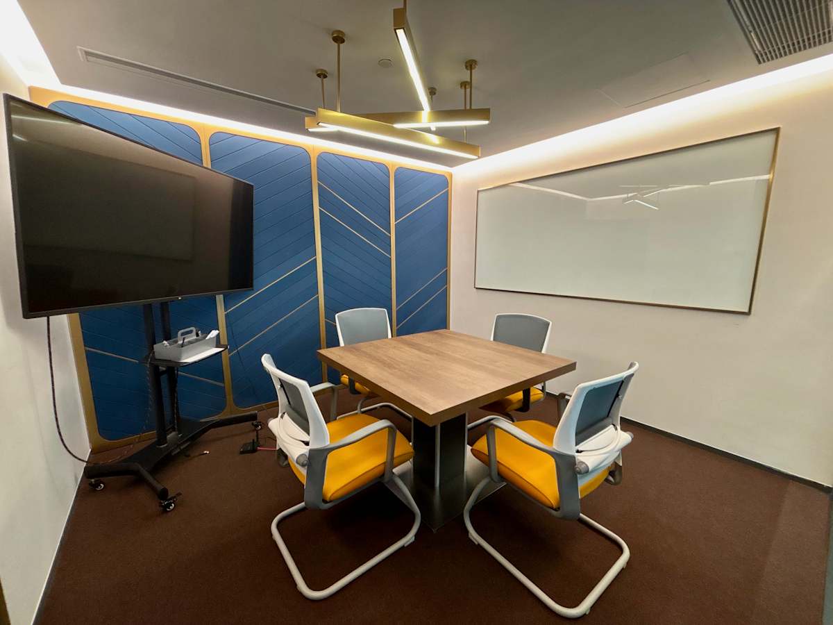 Modern meeting room with sleek design, smart TV, and ample seating in a prime coworking space.