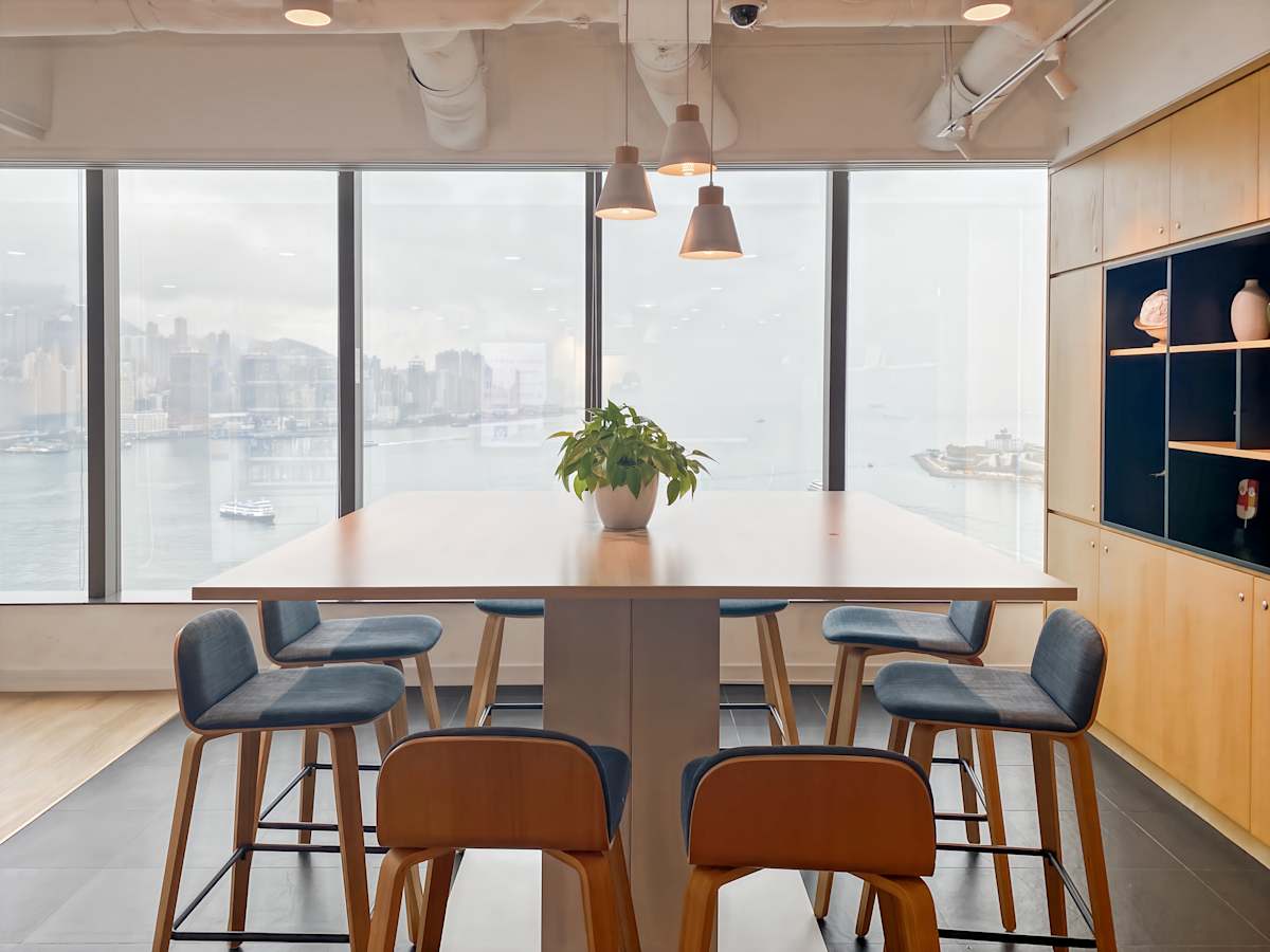 Bright coworking space with panoramic city views, modern seating, and ample natural light.