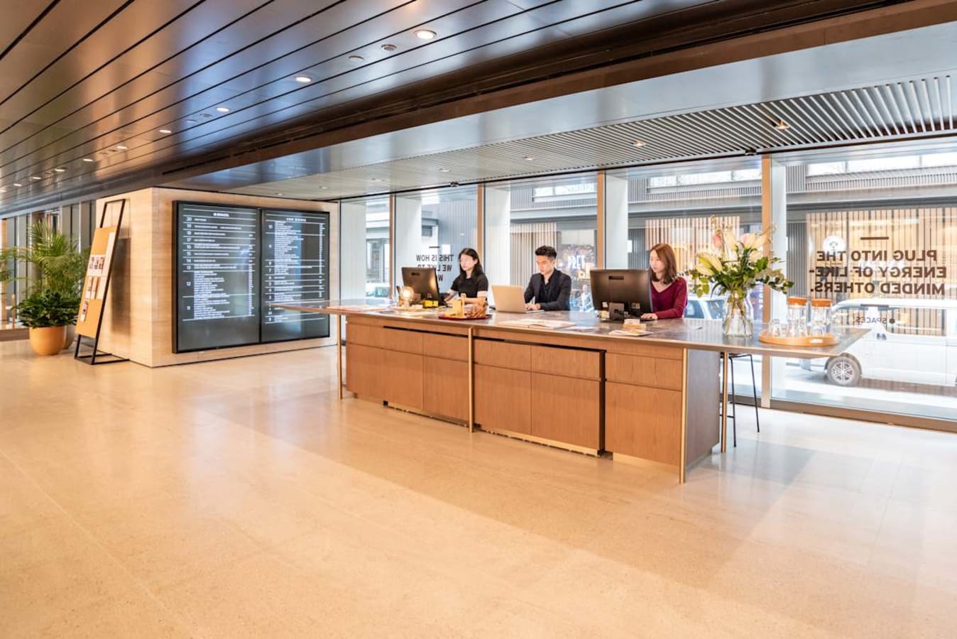 Modern coworking space with elegant reception, ample natural light, and sleek furnishings.