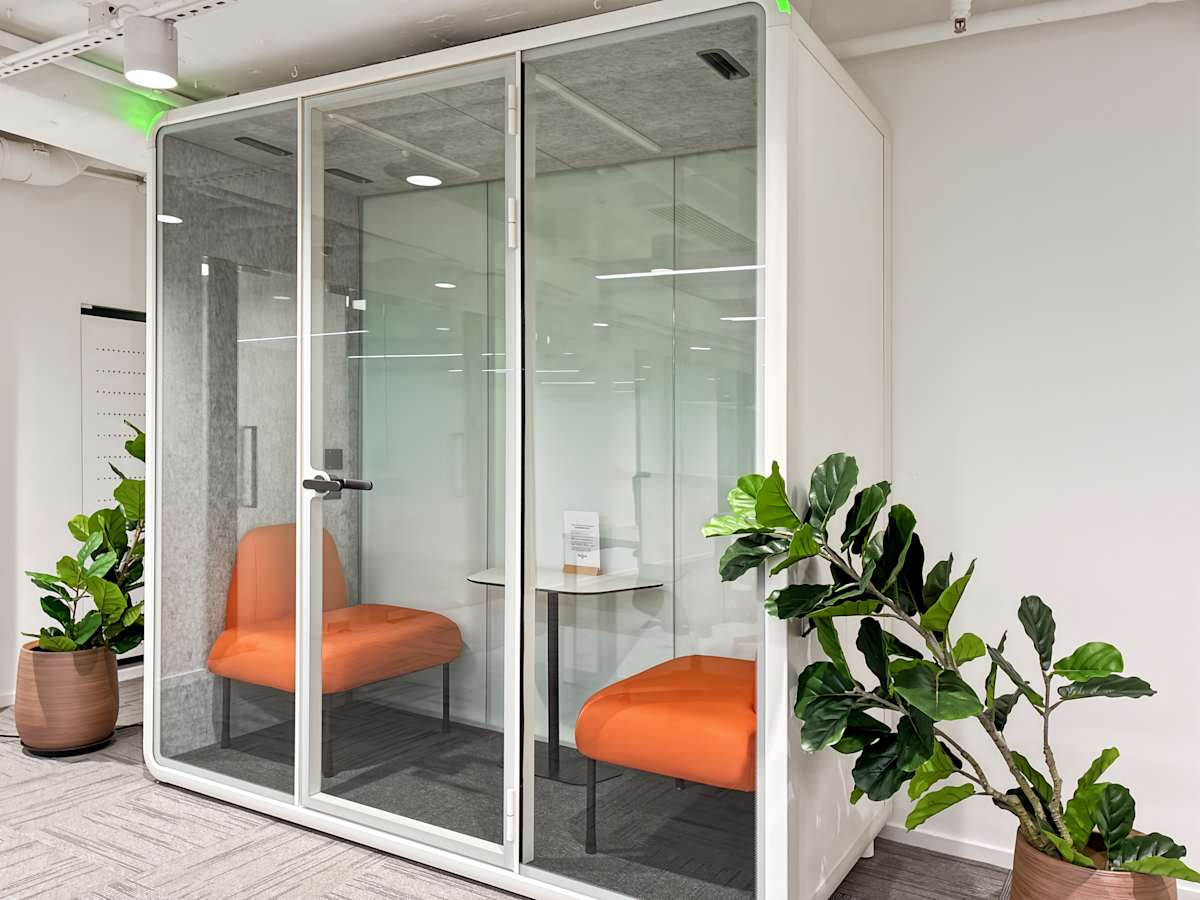 Private meeting pod with vibrant seating, surrounded by greenery for a focused work environment.