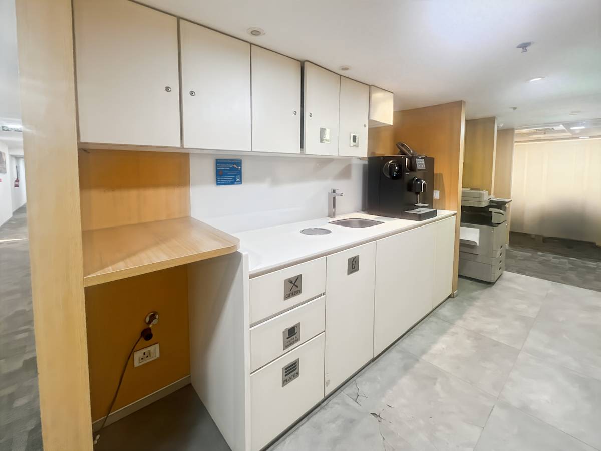 Modern kitchenette in a New Delhi coworking space with ample storage and sleek surfaces.