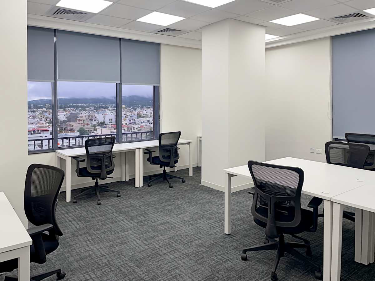 Modern coworking space with city views, ergonomic chairs, and abundant natural light.