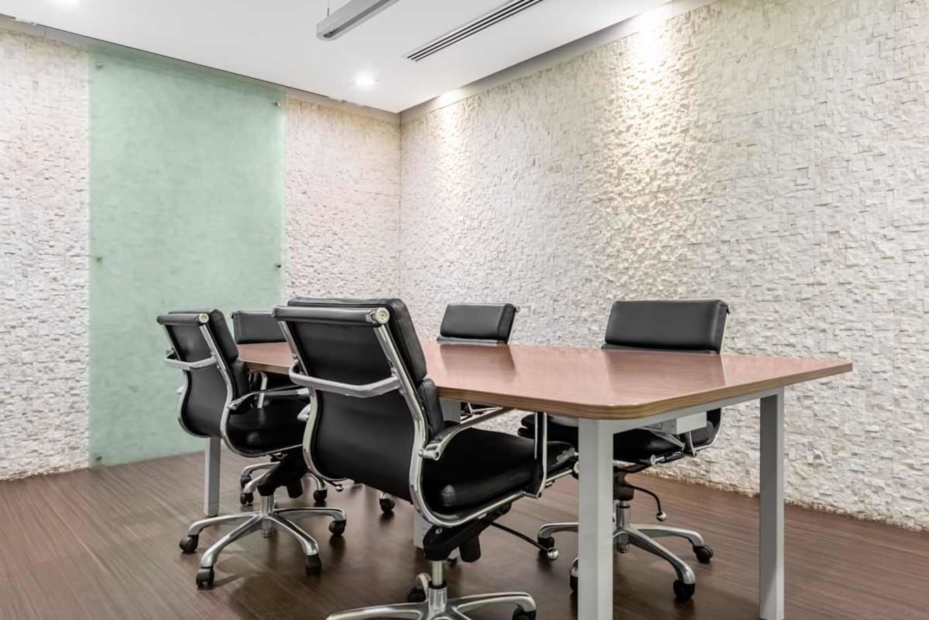 Modern meeting room with sleek chairs and textured walls in a flexible coworking space.