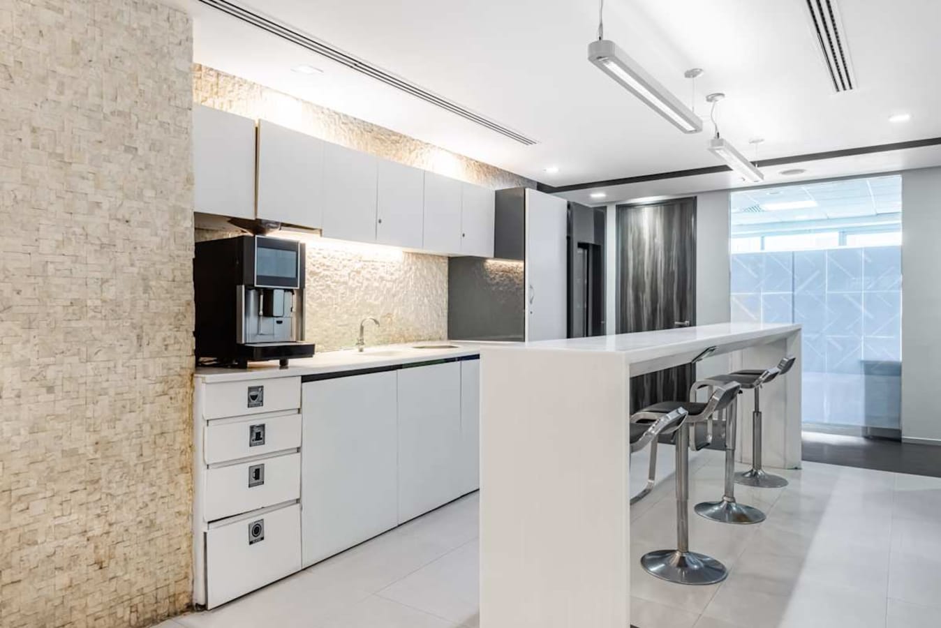 Sleek coworking kitchen area with modern appliances and bar seating, ideal for casual meetings.
