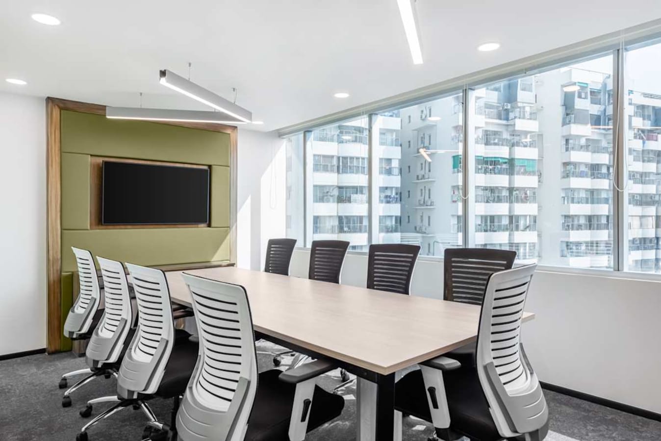 Modern meeting room with ample natural light, ergonomic chairs, and sleek design. Ideal for collaboration.