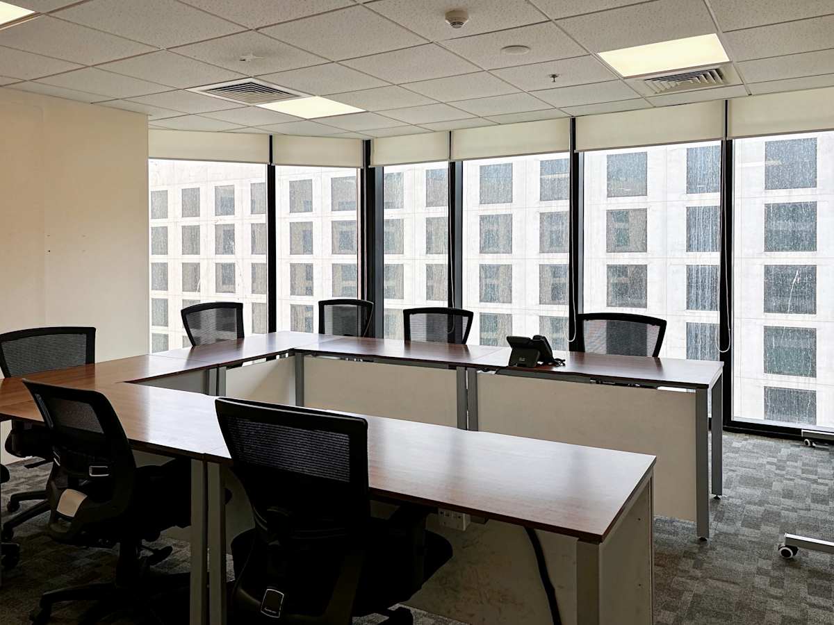 Modern coworking space with large windows, natural light, and ergonomic seating.